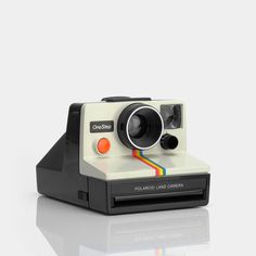 an old polaroid camera sitting on top of a white table next to a wrench