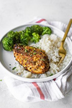 a white plate topped with rice and meat next to broccoli on a towel