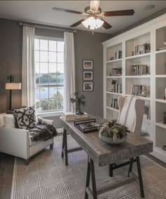 a living room filled with furniture and bookshelves next to a window covered in curtains