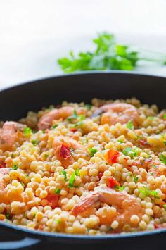 a skillet filled with shrimp and corn on top of a table next to parsley