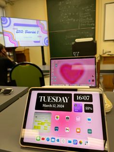 two laptops sitting on top of a table in front of a chalkboard wall