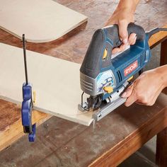 a person using a jig saw to cut plywood planks on a table