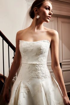 a woman in a wedding dress is standing on the stairs