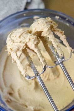 two metal whisk attachments in a blue bowl filled with batter and cream