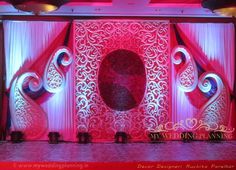 a stage set up for a wedding with red and white decorations on the walls,