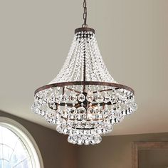 a chandelier hanging from the ceiling in a room with a round window behind it