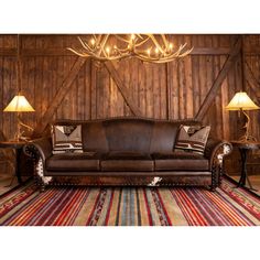 a brown leather couch sitting on top of a rug next to two tables and lamps