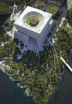 an aerial view of a large building surrounded by trees and bushes, with water surrounding it