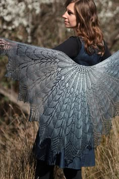 a woman standing in tall grass holding a shawl