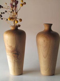 two wooden vases sitting next to each other with flowers in them on a table