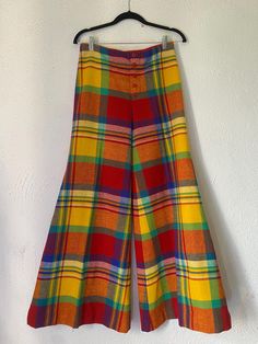 This is an amazing pair of true vintage plaid bellbottoms. They feature a super wide bellbottom leg and have a pleat down each leg. They have a button fly, 5 red buttons. No pockets and no stretch, they feel like wool but there is no content label. The label shows that they are vintage and say they are a size 10, but please check measurements. This is not a modern size 10, fits more like a small. Label also states they are dry clean only. They are unlined. There are some small stains as shown in pictures, but they are barely noticeable when worn!  Measurements: (all taken while flat) Waist 14.5" Hip 18" Length 41" Bellbottom hem 18" (hem can be let out, see pic) Rise 11.5" Inseam 31.5" Outer seam 41" Please let me know if you have any questions! Red Yellow Outfit, Vintage Style Multicolor Full-length Bottoms, 70s Inspired Full-length Fall Pants, 60s Rainbow, Vintage Yellow Wide-leg Bottoms, 70s Plaid Pants, 70s Outfits Ideas, Retro Plaid Wide-leg Pants, Groovy Clothes