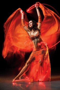 a woman in an orange dress is dancing