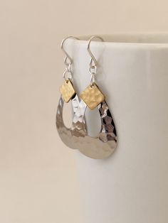 These teardrop shaped dangle earrings are lightweight and fun to wear.  Designed with a silver-plated hammered brass teardrop and topped with a hammered brass accent.   Sterling silver ear wire Mixed metal earrings for every day. Includes cloth storage pouch, gift box, and cloth ribbon.  Our brass jewelry is nickel-free, lead-free and cadmium-free. Earring Drop: 2.5 inches or approx. 60mm Dimensions: Silver teardrop measures 0.75 inches across Minimalism simple style Casual earrings Everyday ear Hammered Metal Jewelry Clasps, Everyday Earrings Silver, Hammered Metal Jewelry, Cloth Storage, Mixed Metal Earrings, Casual Earrings, Earrings Everyday, Mixed Metal Jewelry, Hammered Brass