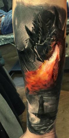 a man's leg with a dragon on it and fire coming out of his mouth