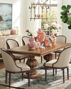 a dining room table with chairs and vases on it