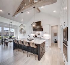 a large kitchen with an island in the middle and two pendant lights hanging from the ceiling