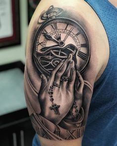 a man's arm with a clock and praying hands tattoo on the left shoulder