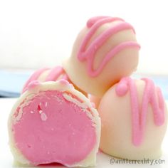 three pink and white chocolates with icing on them sitting next to each other