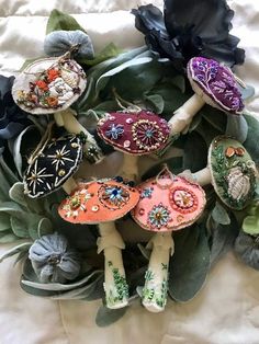 several different colored mushrooms sitting on top of a white cloth covered bed next to black flowers