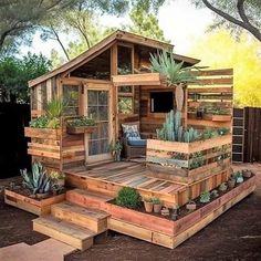 a small house made out of wooden pallets with succulents and plants