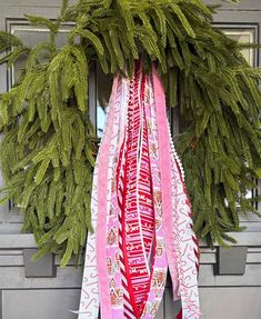 a wreath with ribbons hanging from it's front door