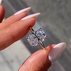 a woman's hand holding an engagement ring with two diamonds on it and one diamond in the middle