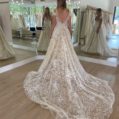 a woman standing in front of a mirror wearing a wedding dress with an open back