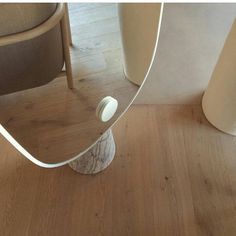 a mirror sitting on top of a wooden floor next to a chair