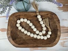 a wooden tray with white beads and tassels