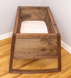 a wooden box with a white towel in it on the floor next to a wall