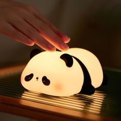 a person touching a light that is shaped like a panda bear on top of a table