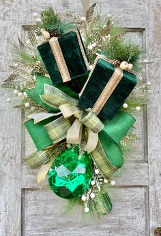 a green christmas ornament hanging on a door with presents tied to the front