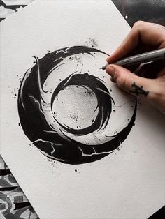 a person is drawing with black ink on white paper and has a pen in their hand