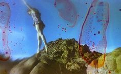 a woman standing on top of a rock covered in pink and orange inks with her arms outstretched