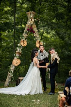 a bride and groom standing in front of an outdoor ceremony arch