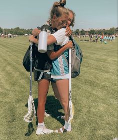 two women hugging each other in the middle of a field