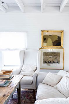 a living room filled with furniture and a painting hanging on the wall above a coffee table