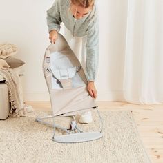 a woman is setting up her baby's stroller on the floor in front of a white wall