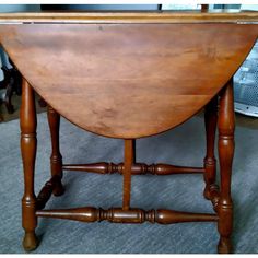 an old wooden table with two legs and a curved top on carpeted flooring