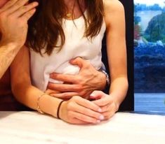 a man and woman sitting next to each other holding their hands over their stomachs