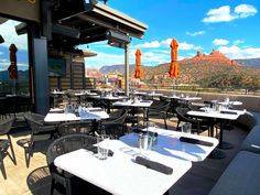 an outdoor dining area with tables, chairs and umbrellas on the roof overlooking mountains