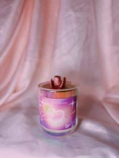 a candle that is sitting on top of a white cloth with pink and purple colors