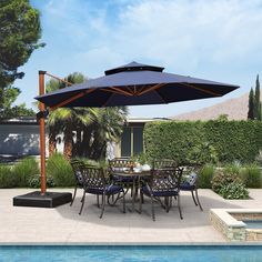 an outdoor dining table with umbrella next to a swimming pool