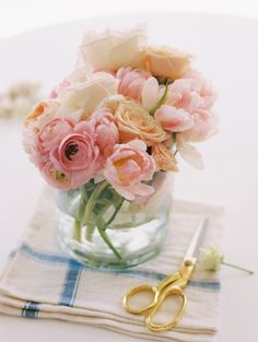 a vase filled with lots of pink flowers on top of a white tablecloth covered table