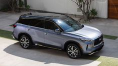 a silver suv is parked in front of a house with plants on the side walk