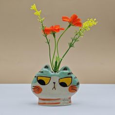 a cat shaped vase with orange flowers in it