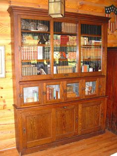 an old wooden bookcase with many books on it in a room filled with wood paneling