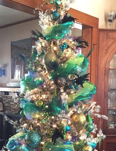 a decorated christmas tree with green and blue ornaments on the top, in front of a mirror