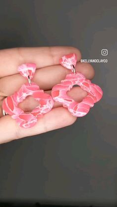 a person holding two pink donuts in their hand with the word love spelled on them