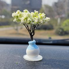 a small vase with flowers in it sitting on the dashboard of a car, next to a window